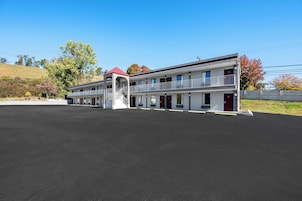 A two-story motel with a central staircase, a covered entrance, and a parking lot.