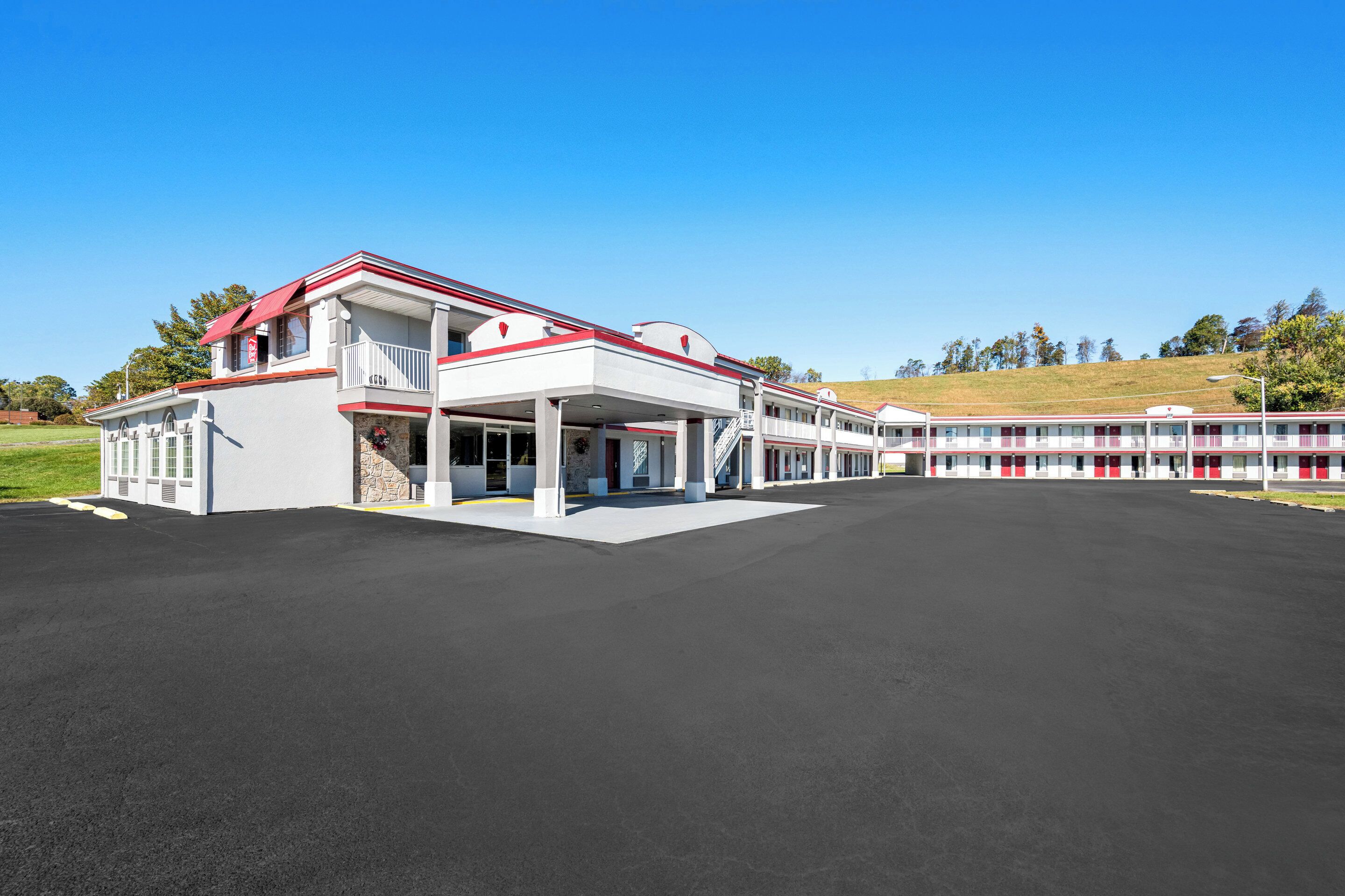 A large hotel with a white facade and red accents, featuring a covered outdoor area and multiple balconies.