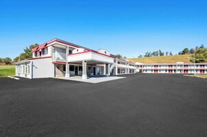 Un hotel grande con fachada blanca y detalles en rojo, que cuenta con un área exterior cubierta y varios balcones.