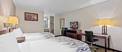 Une chambre d’hôtel avec deux lits, un bureau, une télévision et une lampe.