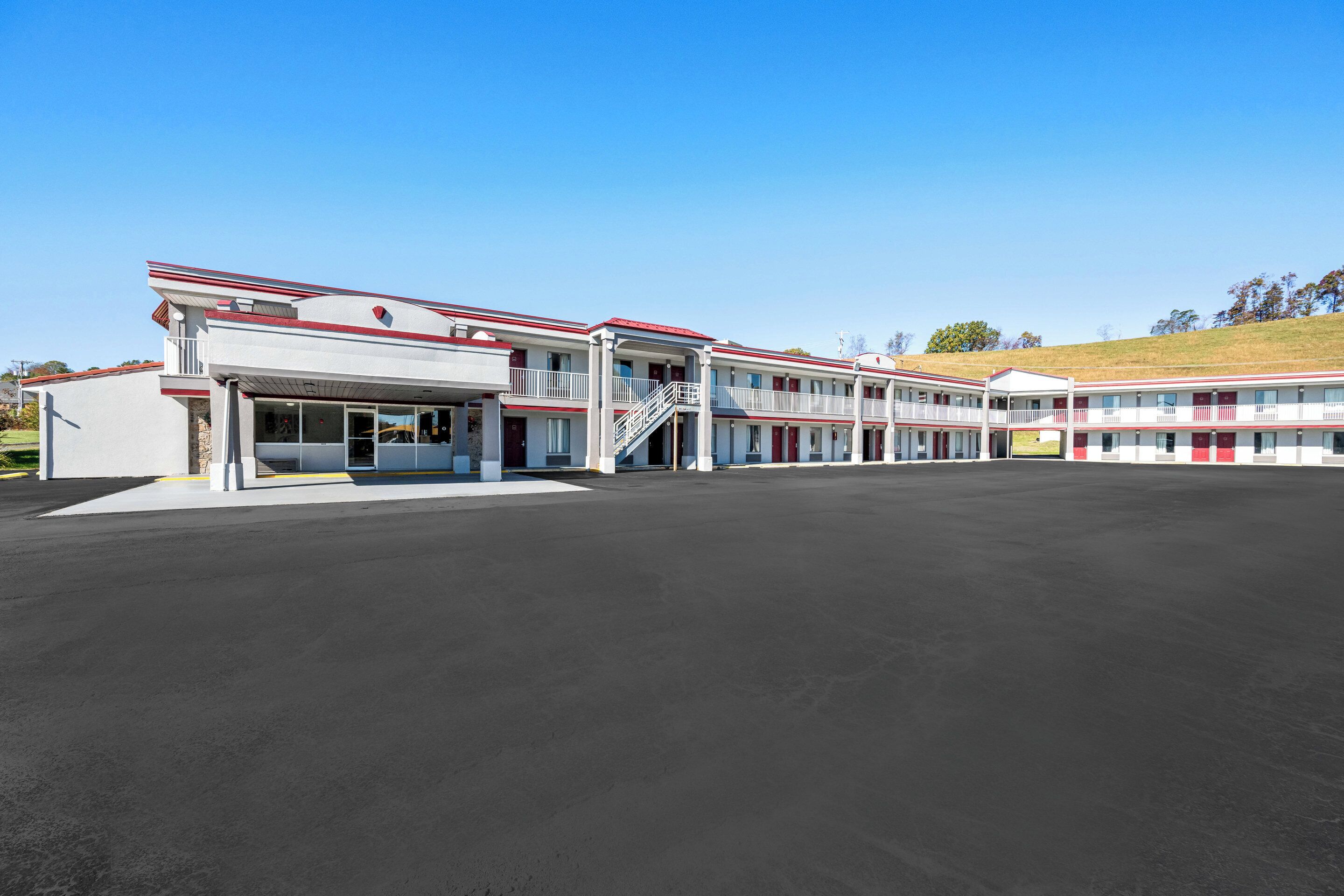 Un motel con entrada central, varios balcones y aparcamiento.