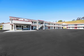 A motel with a central entrance, multiple balconies, and a parking lot. - Red Roof Inn Abingdon (Abingdon)