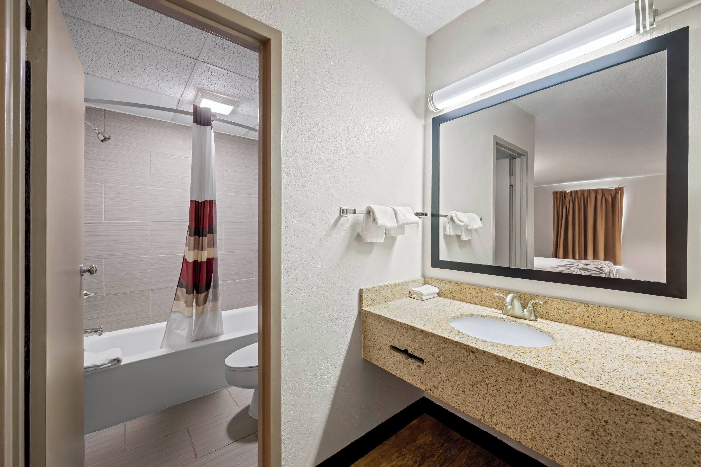 Un baño moderno con bañera, lavamanos y un espejo grande.