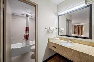 A modern bathroom with a bathtub, a sink, and a large mirror.
