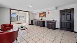 A spacious living area with a kitchen, a red sofa, a small table with a plant, and a large window with a view of the outside. - Red Roof Inn Abingdon (Abingdon)
