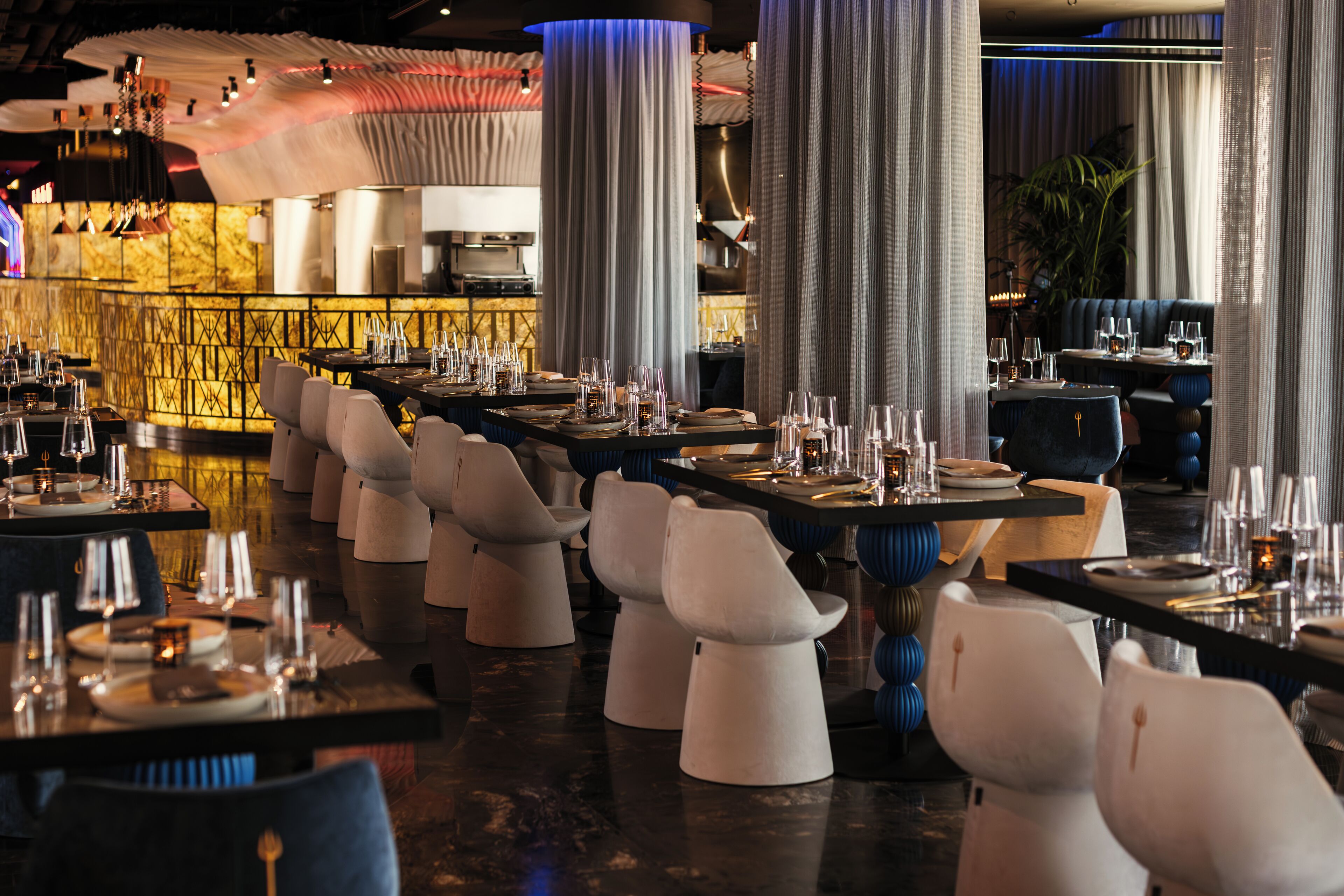 Un ristorante con diversi tavoli e sedie, un'area bar e un arredamento moderno.
