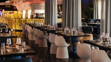 Un ristorante con diversi tavoli e sedie, un'area bar e un arredamento moderno.