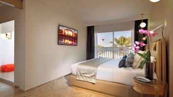 Ein modernes Hotelzimmer mit einem großen Bett, Meerblick, einem gerahmten Bild an der Wand und einem kleinen Tisch mit Blumen.
