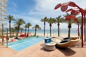 A poolside area with a view of the beach, palm trees, and a clear sky. - Ushuaïa Ibiza Beach Hotel - Adults Only - Club Entrance Included (Sant Josep de sa Talaia)