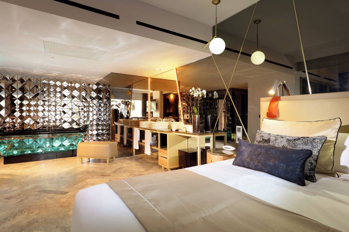Ein modernes Schlafzimmer mit einem großen Bett, einem Schminktisch und einem Badezimmer im Hintergrund.