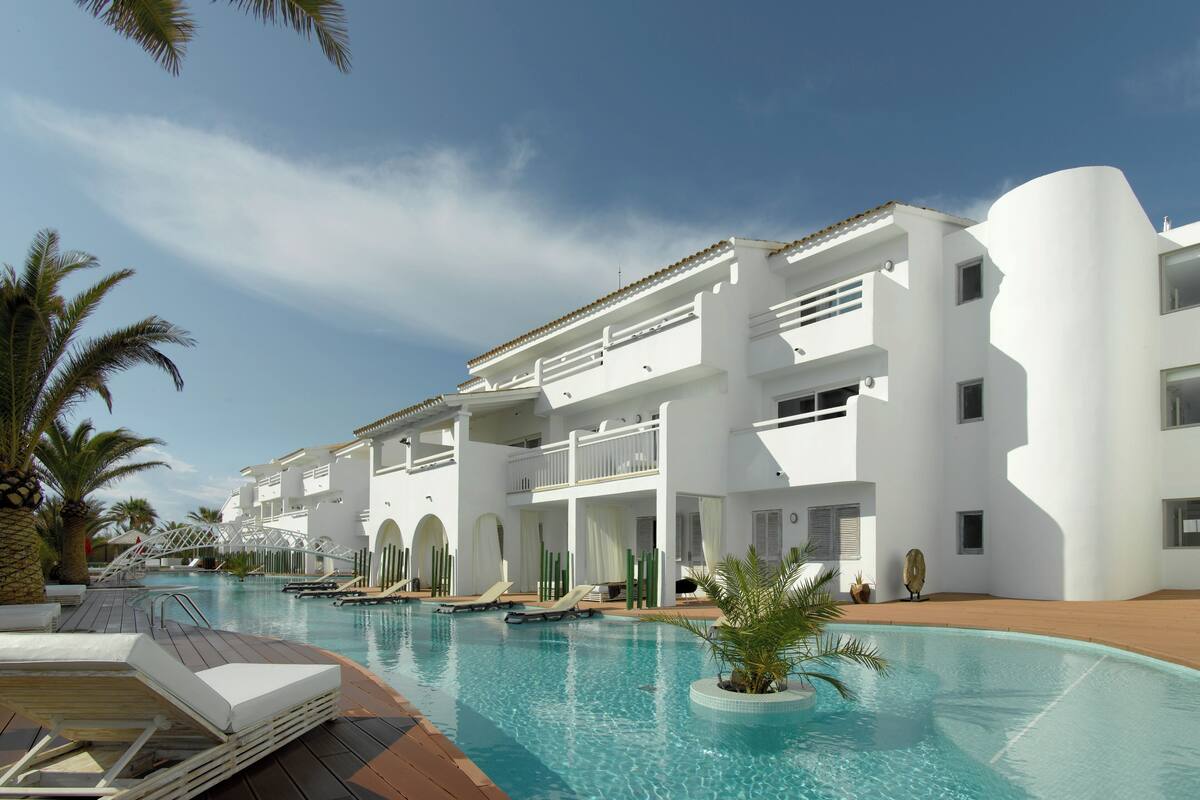 Ein Resort mit Swimmingpool, weißen Gebäuden und Palmen.