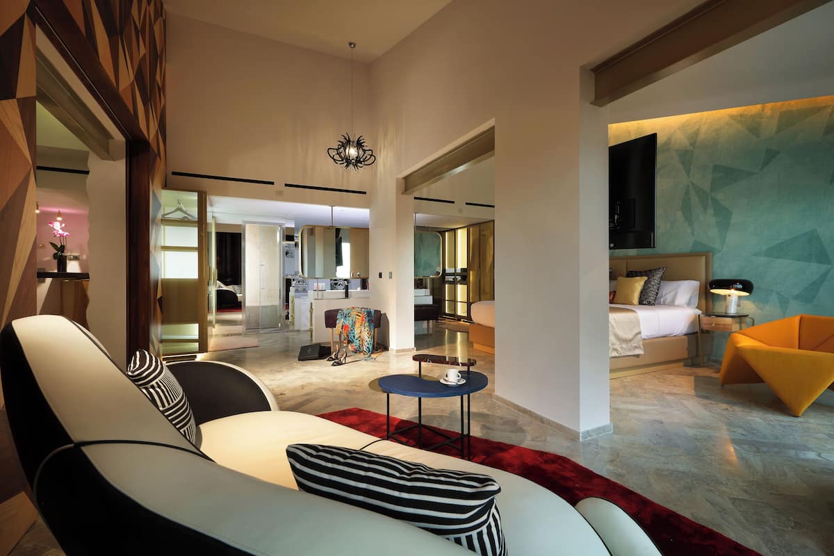 Ein modernes Hotelzimmer mit einem großen Bett, einer Couch, einem kleinen Tisch und einem Fernseher.