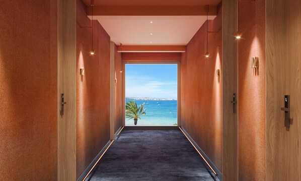 Un pasillo con vista al mar, una palmera y un paisaje urbano distante.