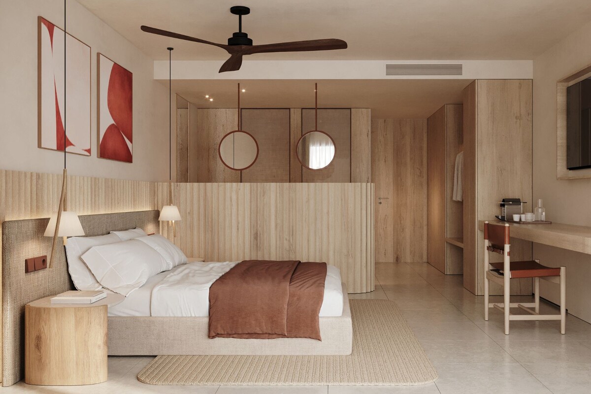 A modern hotel room with a bed, bedside tables, a desk, and a ceiling fan.
