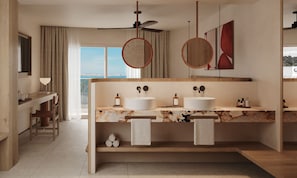 A modern bathroom with two sinks, a ceiling fan, and a view of the sea.