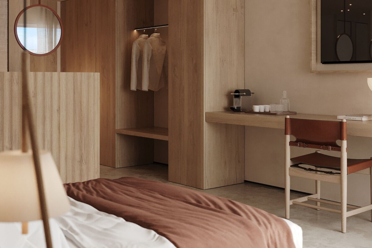 A modern bedroom with a bed, a desk, a chair, a mirror, and a wardrobe.