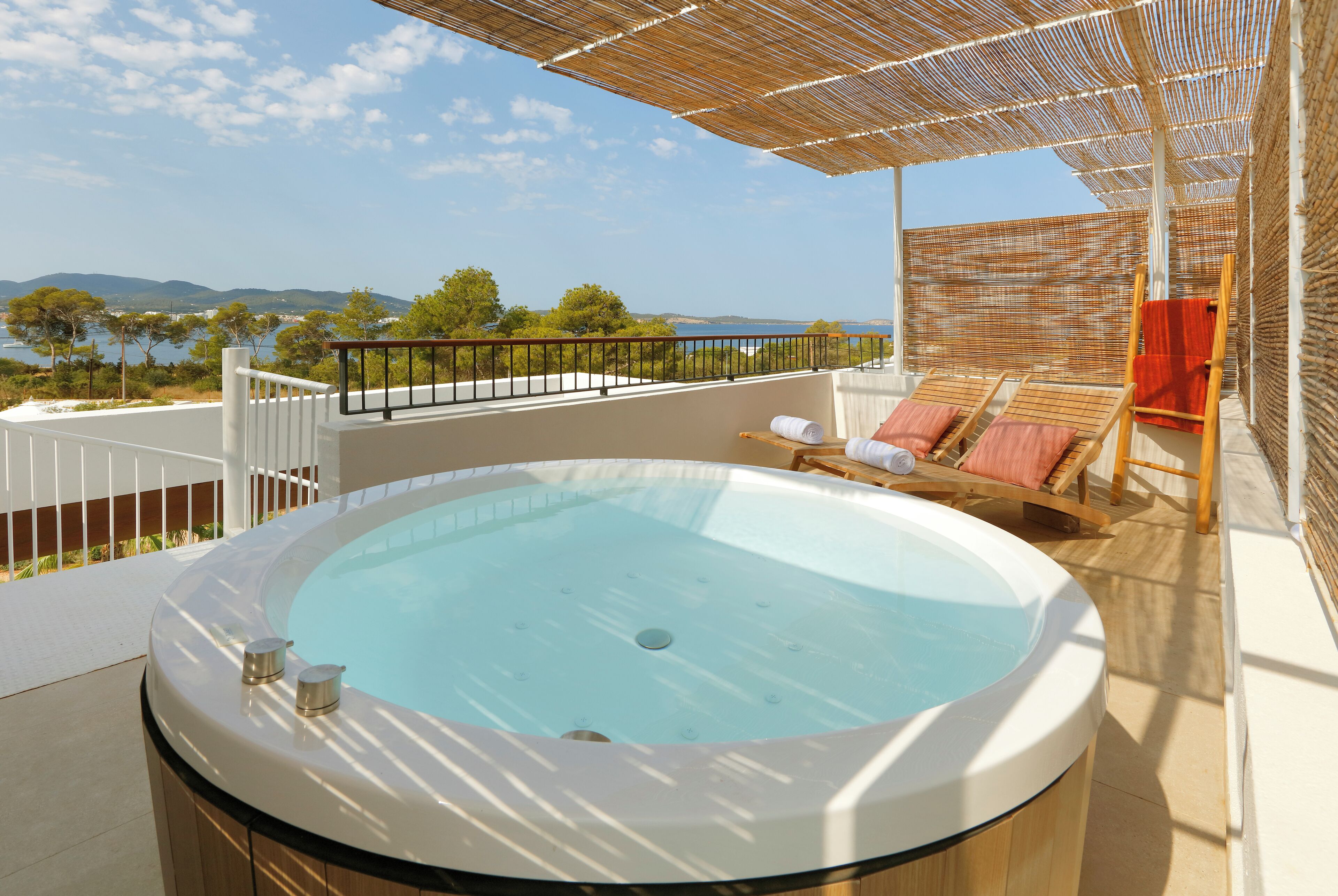 A hot tub on a balcony with a view of the sea and mountains.