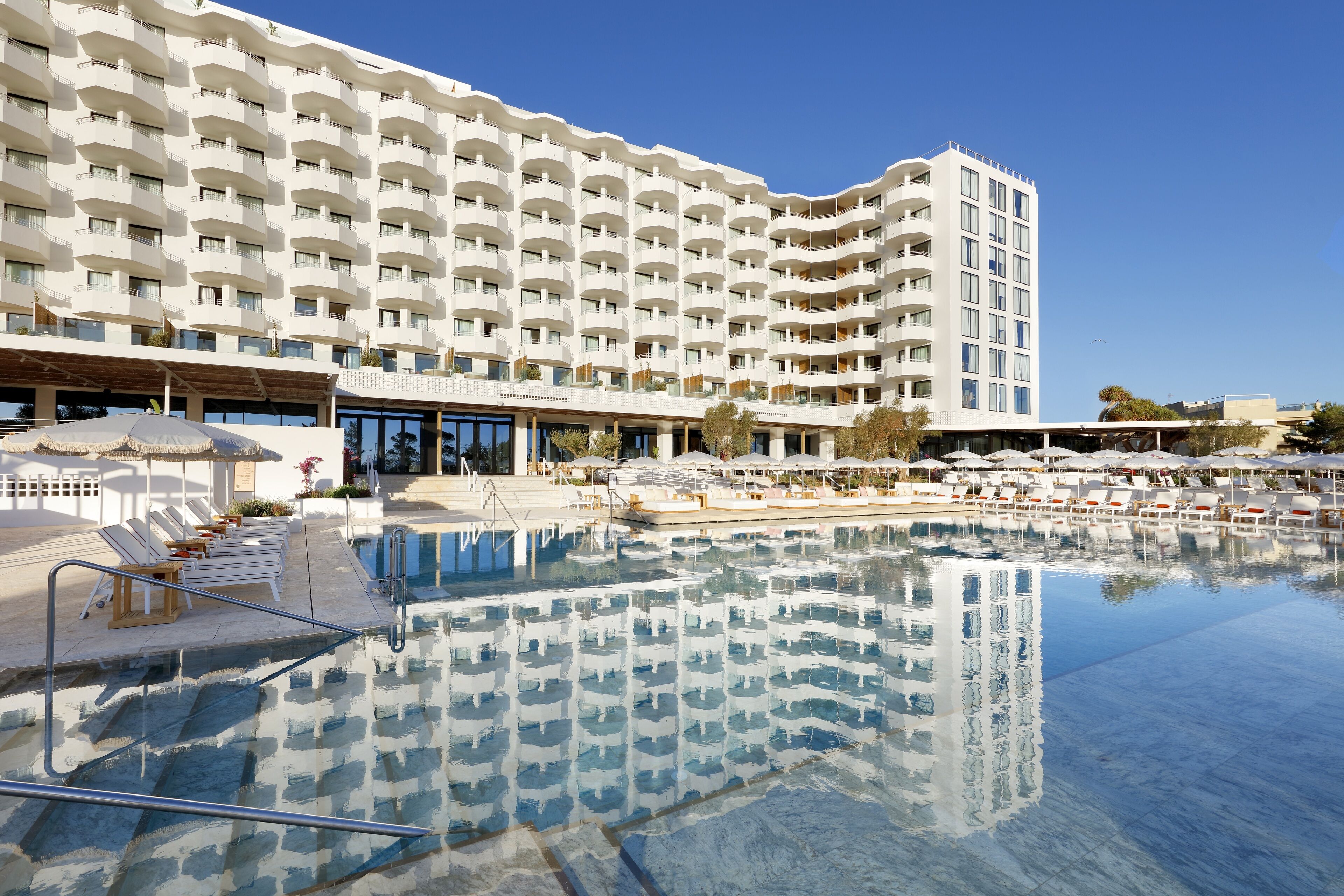Ein großes Hotel mit Poolbereich, mehreren Balkonen und Sitzgelegenheiten im Freien.