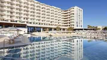 Ein großes Hotel mit Poolbereich, mehreren Balkonen und Sitzgelegenheiten im Freien.