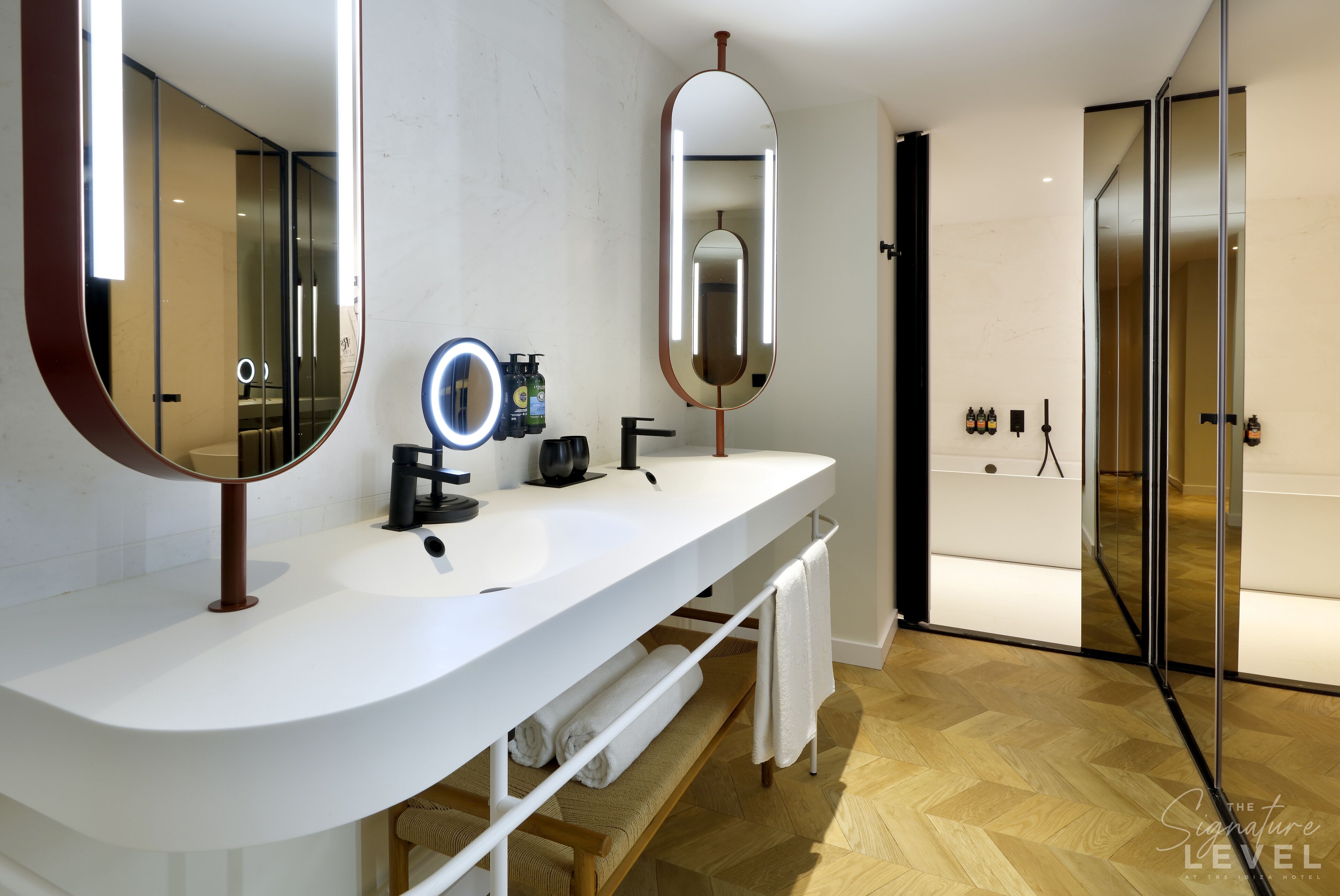 Ein modernes Badezimmer mit einem weißen Waschtisch, einem großen Spiegel und einer Duschkabine aus Glas.