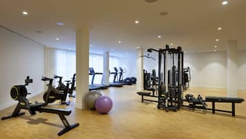 Un gimnasio con máquinas de cardio, pesas libres y una estructura para sentadillas.