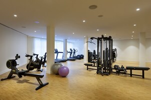 Un gimnasio con máquinas de cardio, pesas libres y una estructura para sentadillas.