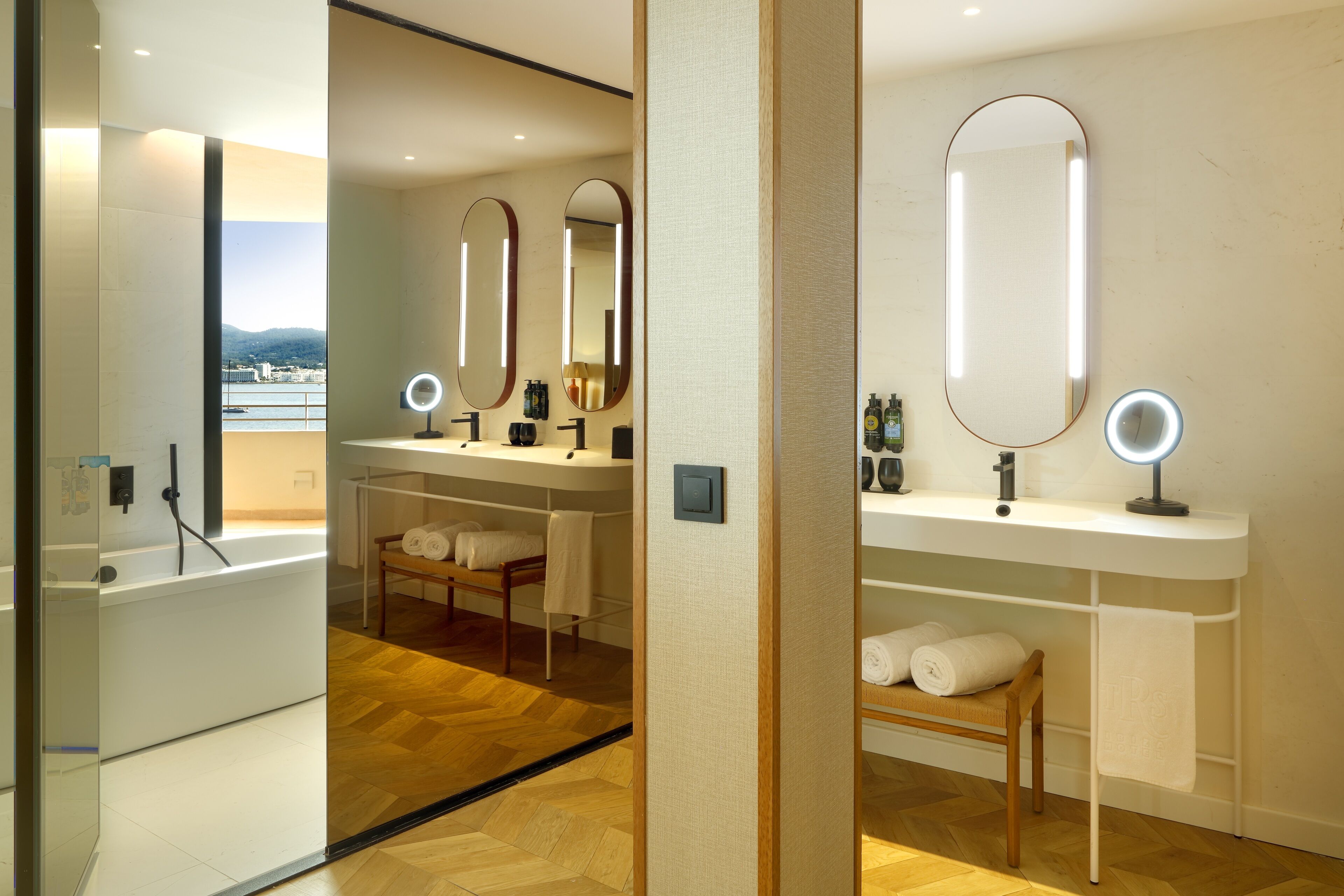 Un baño moderno con una bañera, dos lavamanos y tres espejos.
