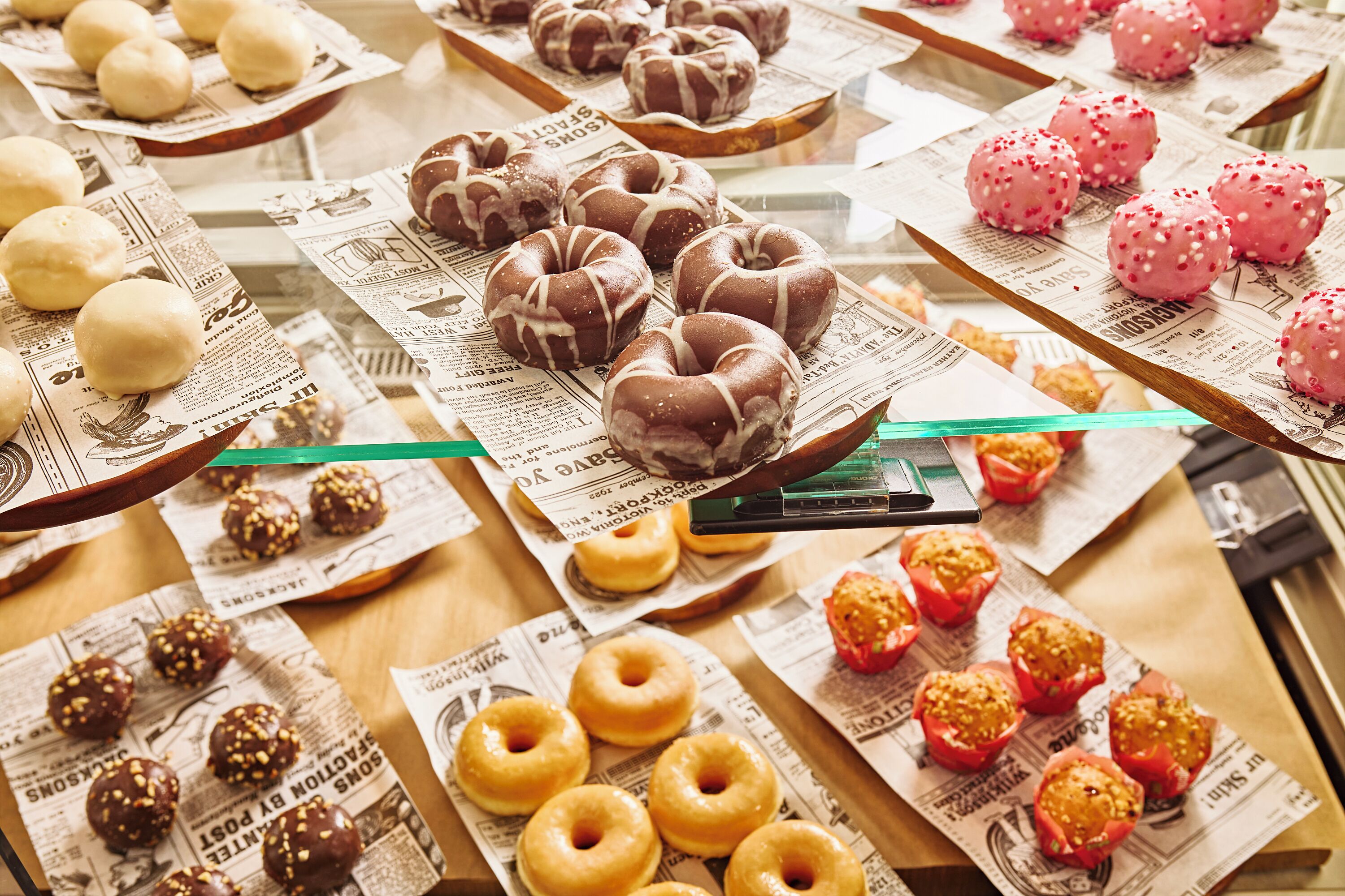 Diversos donuts dispostos em bandejas forradas com jornal.