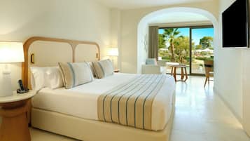 Habitación de hotel con una cama grande, lámparas de noche, una mesita pequeña y vistas al exterior.