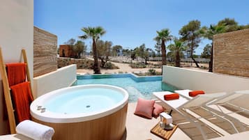 Zona de piscina con jacuzzi, sillas de descanso y toallas.