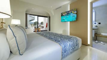 A modern hotel room with a large bed, a TV mounted on the wall, and a view of the outdoors through a large window.