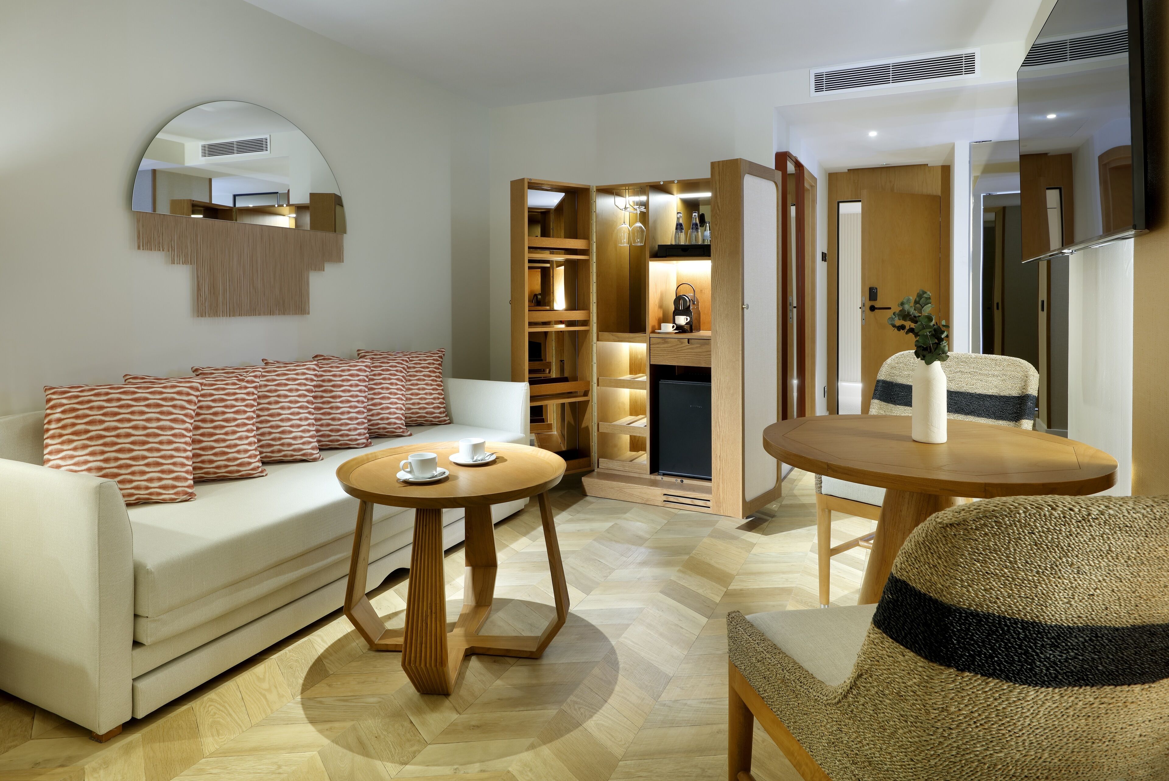 Een moderne woonkamer met een bank, een ronde houten tafel en een rieten stoel.