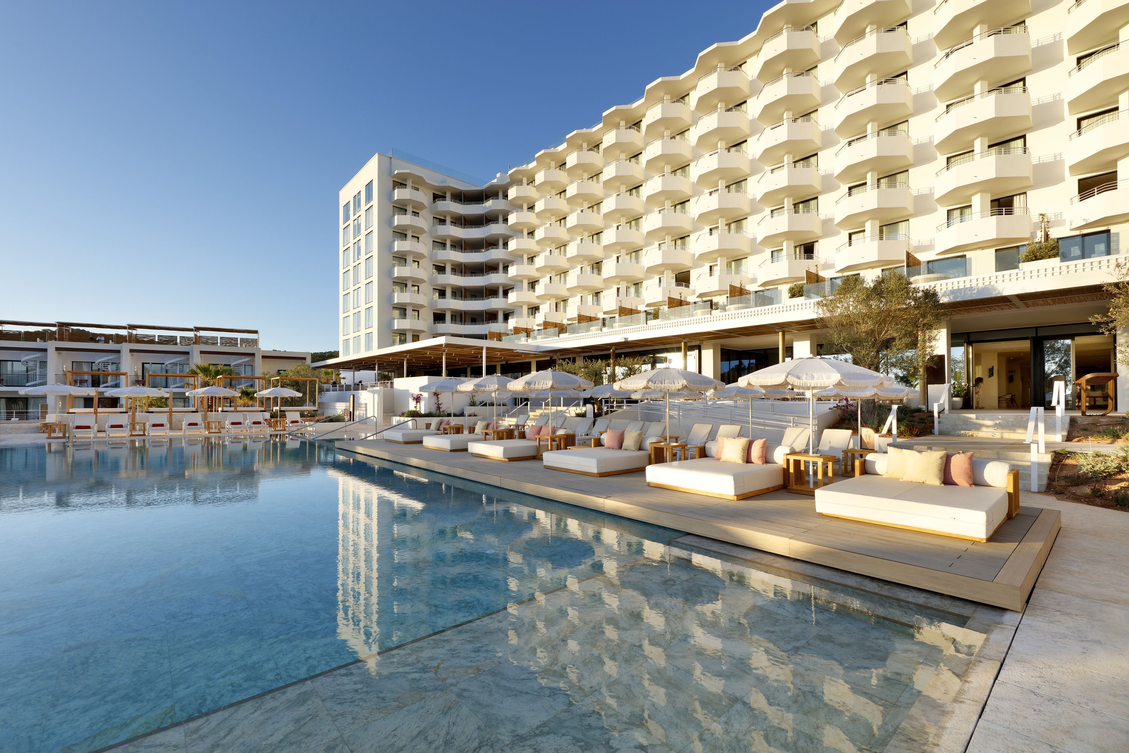 A hotel with a swimming pool, outdoor seating, and multiple balconies.