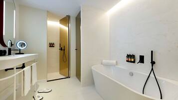 Un baño moderno con una bañera independiente, un tocador con espejo e iluminación, y zona de ducha.