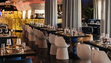 Un restaurant doté de nombreuses tables et chaises, d’un bar et d’un décor intérieur moderne.