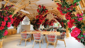 A restaurant with a bamboo archway, red flowers, and white wicker chairs. - The Unexpected Ibiza Hotel - Ushuaïa Club entrance included (Sant Josep de sa Talaia)