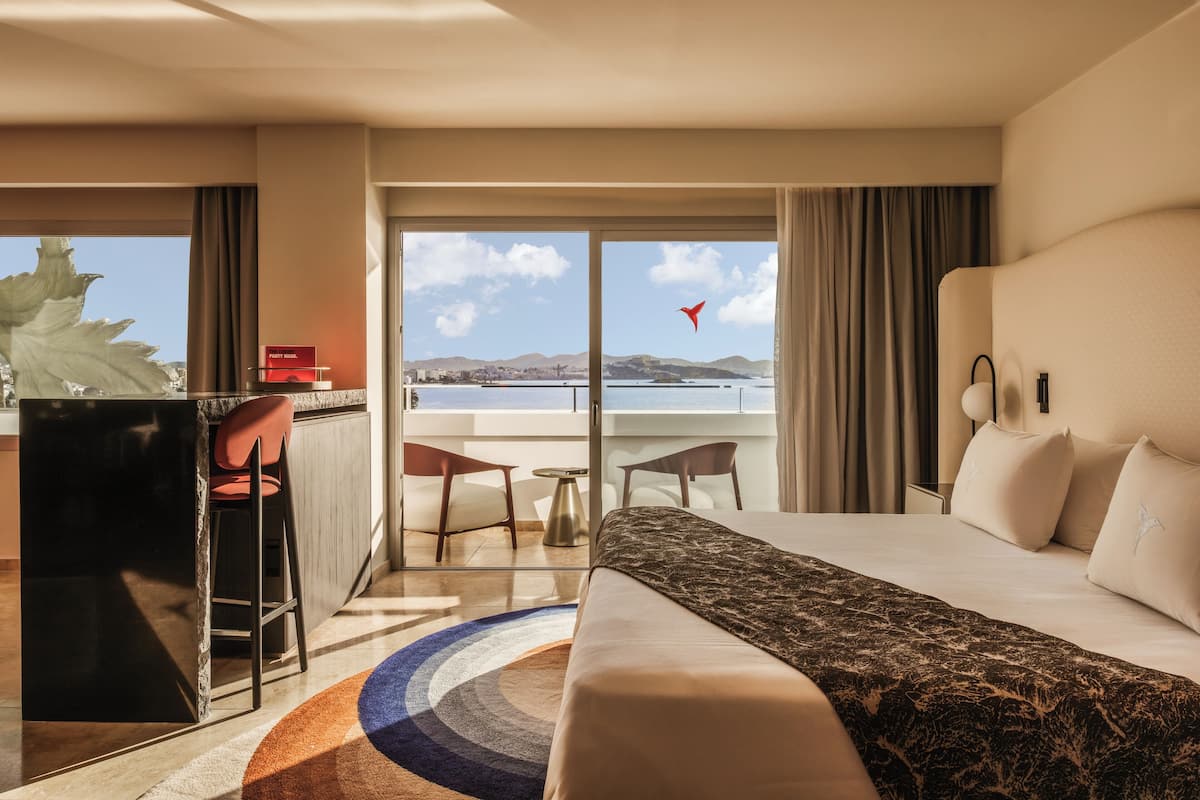 Ein Hotelzimmer mit Bett, Schreibtisch und Meerblick.