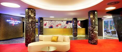 A modern lobby with a red carpet, a white sofa, and a reception desk.