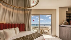 A hotel room with a bed, a balcony with a view of the sea, and a small seating area. - The Unexpected Ibiza Hotel - Ushuaïa Club entrance included (Sant Josep de sa Talaia)