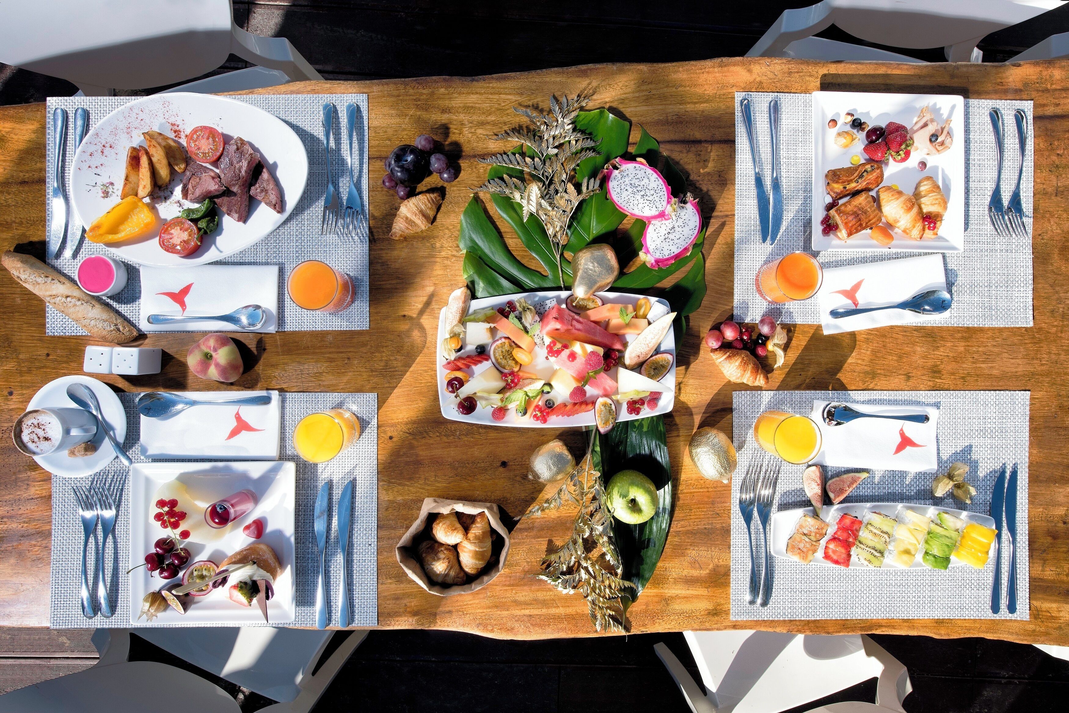 A breakfast table with plates of food, cutlery, and drinks.