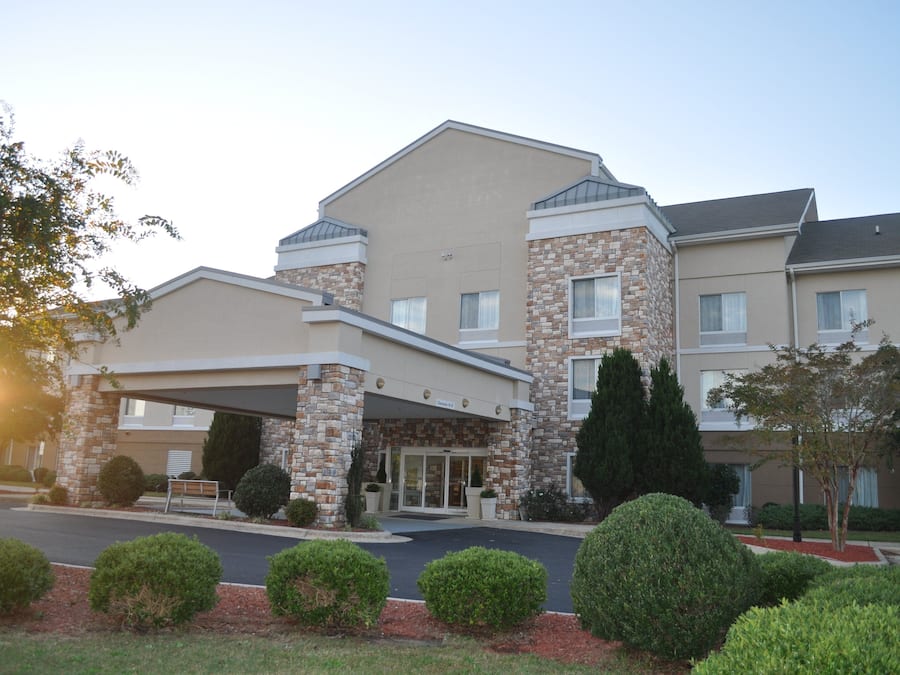A hotel with a covered entrance, stone facade, and multiple windows.