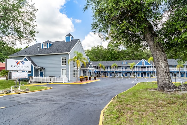 A motel with a Gator Town Inn sign, a fenced parking area, and a row of blue buildings with balconies.