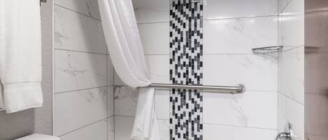 A modern bathroom with a white toilet, a bathtub, and a shower area.