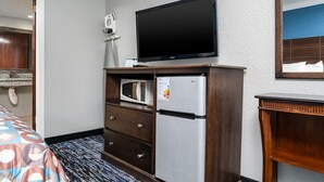 A hotel room with a flat-screen TV, a refrigerator, a microwave, and a wooden dresser. - Gator Town Inn (Gainesville)