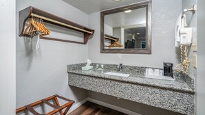 A bathroom with a granite countertop, a mirror, a towel rack, and a hairdryer.