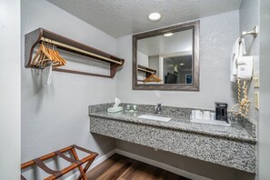 A bathroom with a granite countertop, a mirror, a towel rack, and a hairdryer.