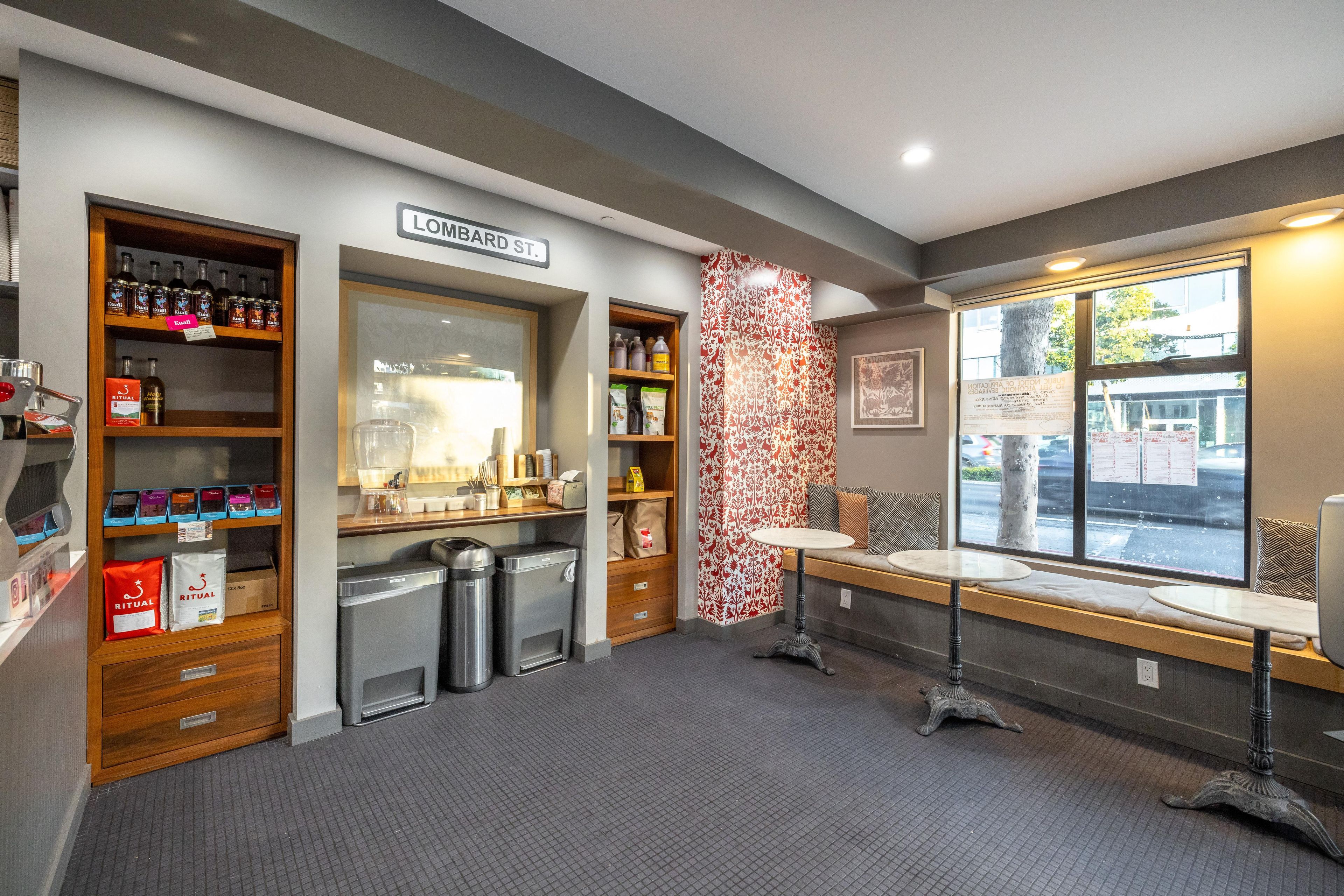 L’intérieur d’un café, avec un espace salon, une machine à café et une fenêtre donnant sur la rue.