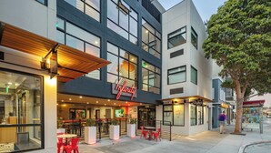 A modern hotel with a prominent Infinity sign, outdoor seating area, and a visible entrance. - Infinity Hotel San Francisco, Tapestry Collection by Hilton (San Francisco)