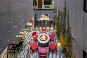 An outdoor patio with a fire pit, red chairs, and a tiled floor. - Infinity Hotel San Francisco, Tapestry Collection by Hilton (San Francisco)