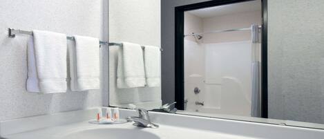 Une salle de bain moderne avec un lavabo blanc, un grand miroir et une douche à parois de verre.